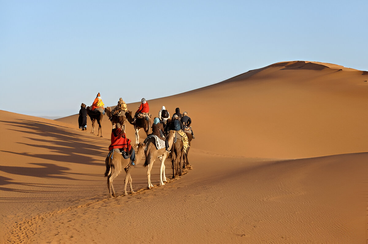 Small group riding camels in the big dunes of Erg Chebbi in Merzouga during a shared 3-day tour from Marrakech Morocco