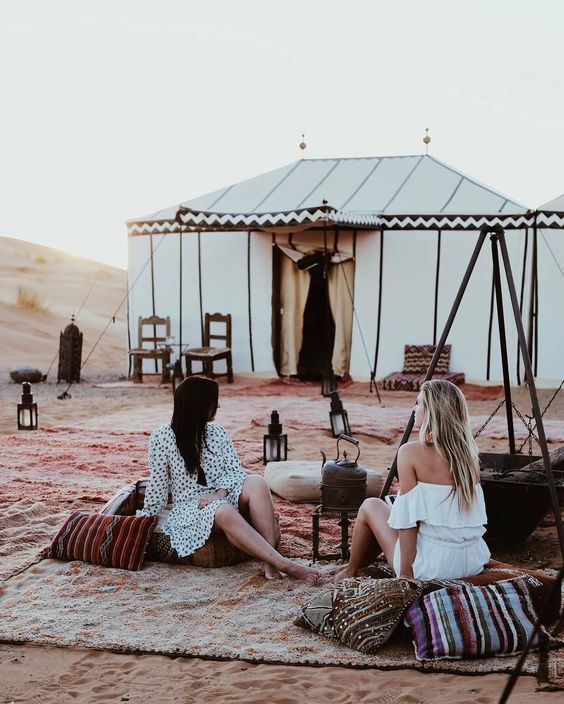 Two women relaxing in a luxury desert camp in Erg Lihoudi Morocco with traditional Berber décor