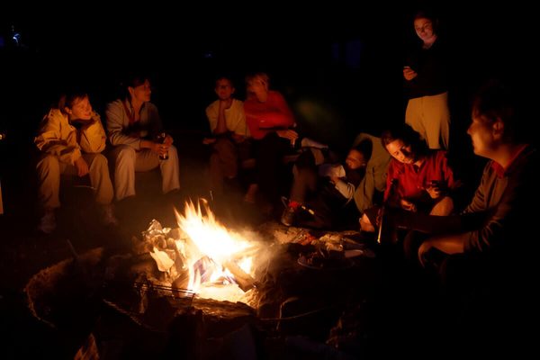 Clients enjoying Berber music around a campfire at night in Zagora Desert under a starry sky