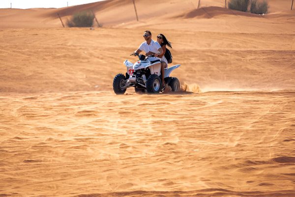 Couple enjoying a thrilling quad bike ride in Zagora desert during the 2-Day Zagora Desert Tour from Marrakech