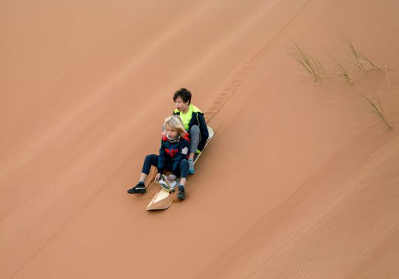 Sandboarding on the Sahara dunes during the 3-day desert tour from Marrakech to Fes.