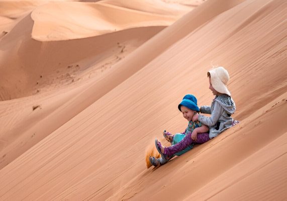 Guests enjoying sandboarding on the golden dunes of the Sahara Desert near Merzouga
