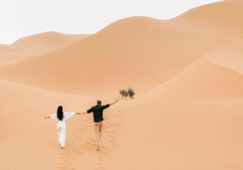 Couple walking in the Sahara dunes during a private desert tour from Ouarzazate