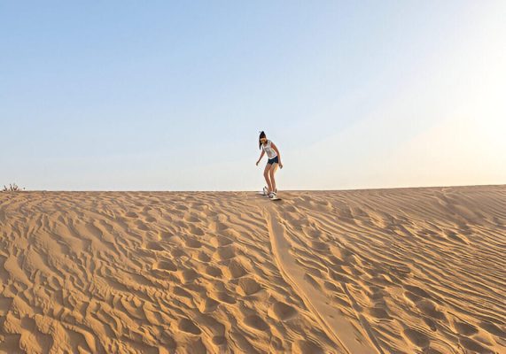 Sandboarding in Erg Lihoudi dunes during a Sahara desert tour from Ouarzazate