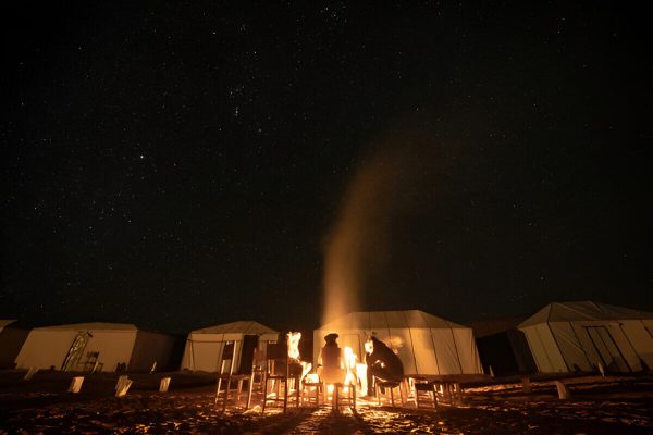 Guests enjoying Berber music around a campfire at Erg Lihoudi during a tour from Zagora