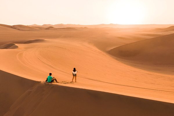 Couple enjoying sunset on the Erg Lihoudi dunes during a tour from Zagora