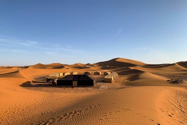 Desert camp surrounded by sand dunes in Erg Lihoudi, Morocco