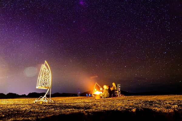 Guests enjoying Berber music around a campfire under the stars at Erg Lihoudi Desert Camp.