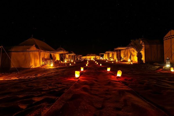 Luxury desert camp at night illuminated by candles in Morocco