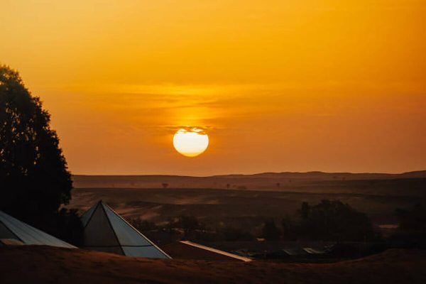 Luxury desert camp among the golden dunes of Erg Lihoudi at sunset