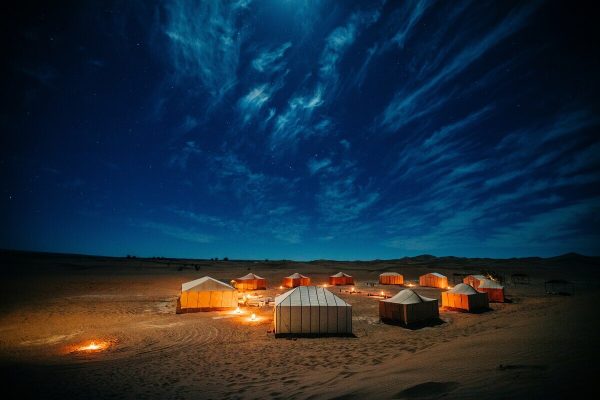 Desert camp illuminated at night beneath the stars in the Moroccan Sahara